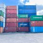 A stack of colorful shipping containers at a port, showcasing various shipping lines and companies.
