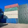 A stack of colorful shipping containers against a clear blue sky, with some containers labeled.
